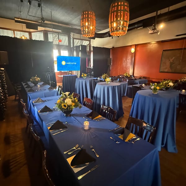 Pignetti's private dining room with blue tablecloths, floral centerpieces, and a welcome screen.