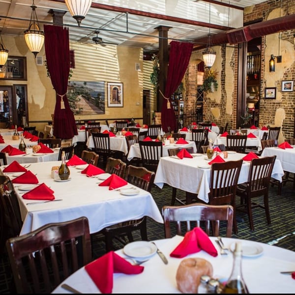 Pignetti's Italian restaurant dining room with white tablecloths, red napkins, and dark wooden chairs.