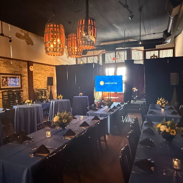 Pignetti's Italian restaurant dining room set for an event with blue tablecloths, floral centerpieces, and a welcome screen.