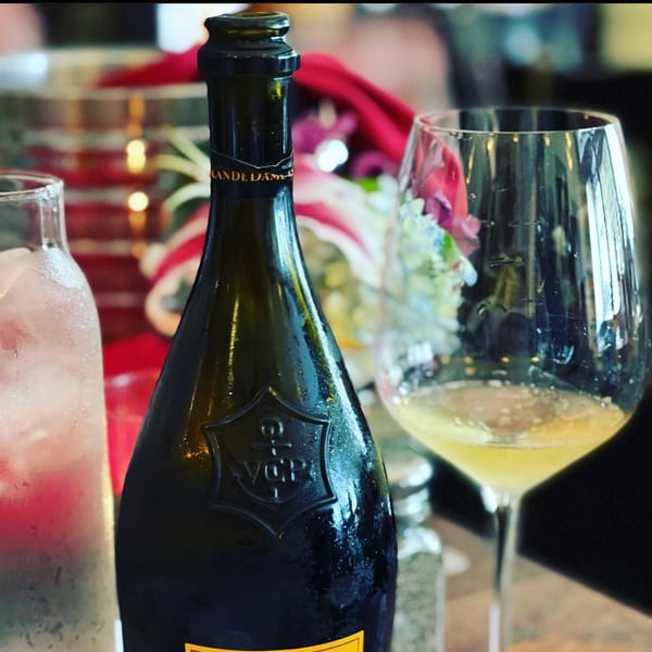 A chilled bottle of champagne and a glass of white wine on a table at Pignetti's.