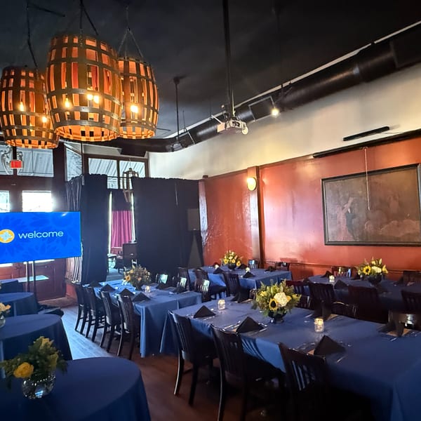 Pignetti's private dining room with blue tablecloths, floral centerpieces, and barrel-shaped light fixtures.