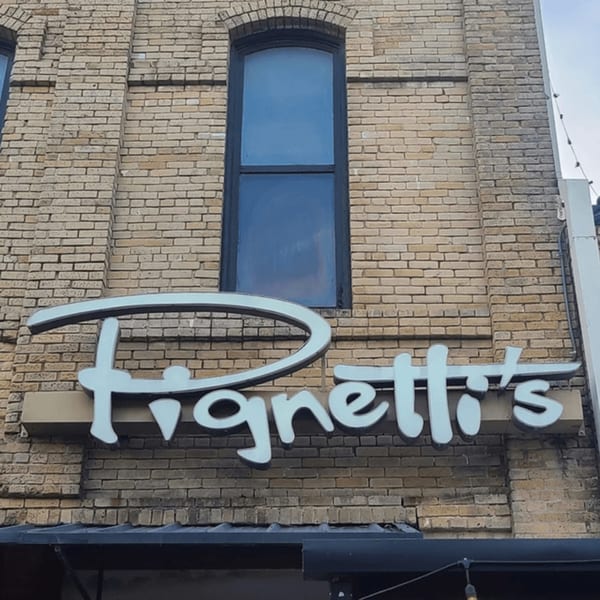 The Pignetti's restaurant sign, with light blue letters, on a brick building facade.