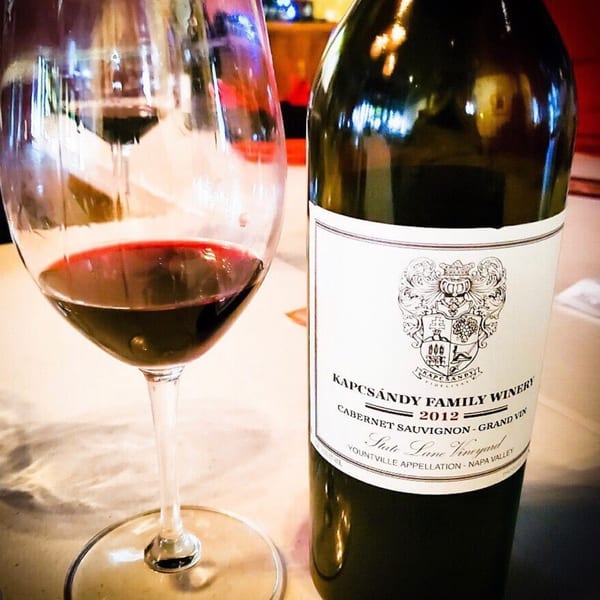 A glass of red wine next to a bottle of Kapcsandy Family Winery Cabernet Sauvignon.