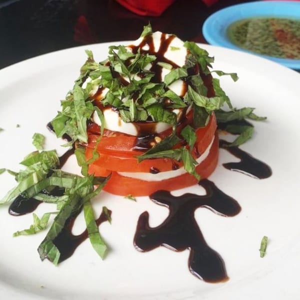 Pignetti's Italian Caprese salad with stacked tomatoes, mozzarella, basil, and balsamic glaze.