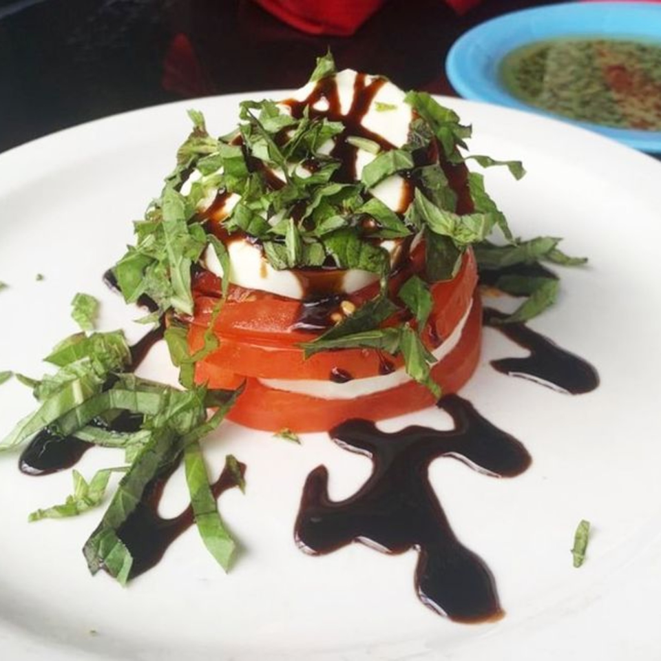 Pignetti's Italian Caprese salad with stacked tomatoes, mozzarella, basil, and balsamic glaze.
